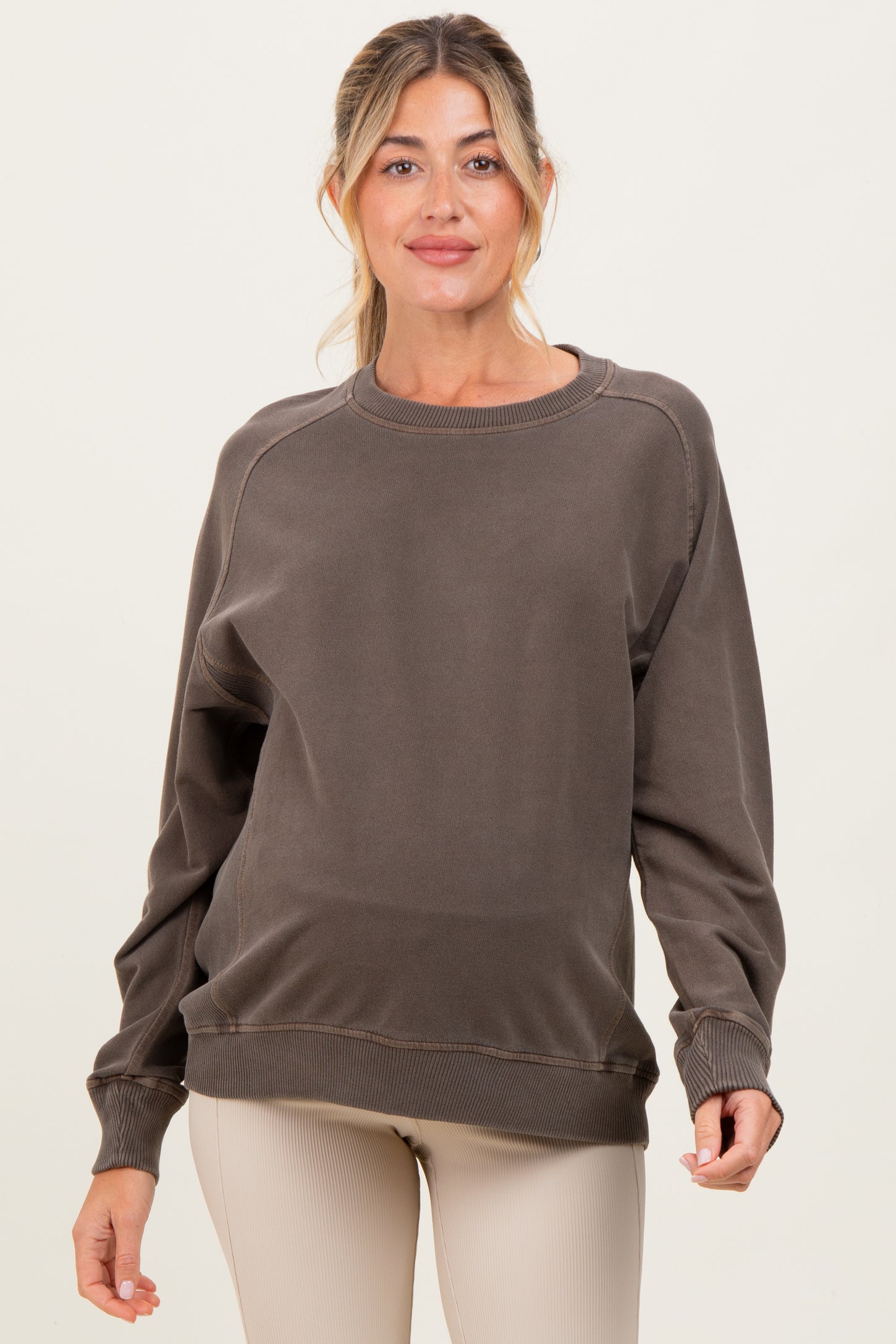 woman wearing a brown maternity sweatshirt with long sleeves and relaxed fit, showcasing a baby bump