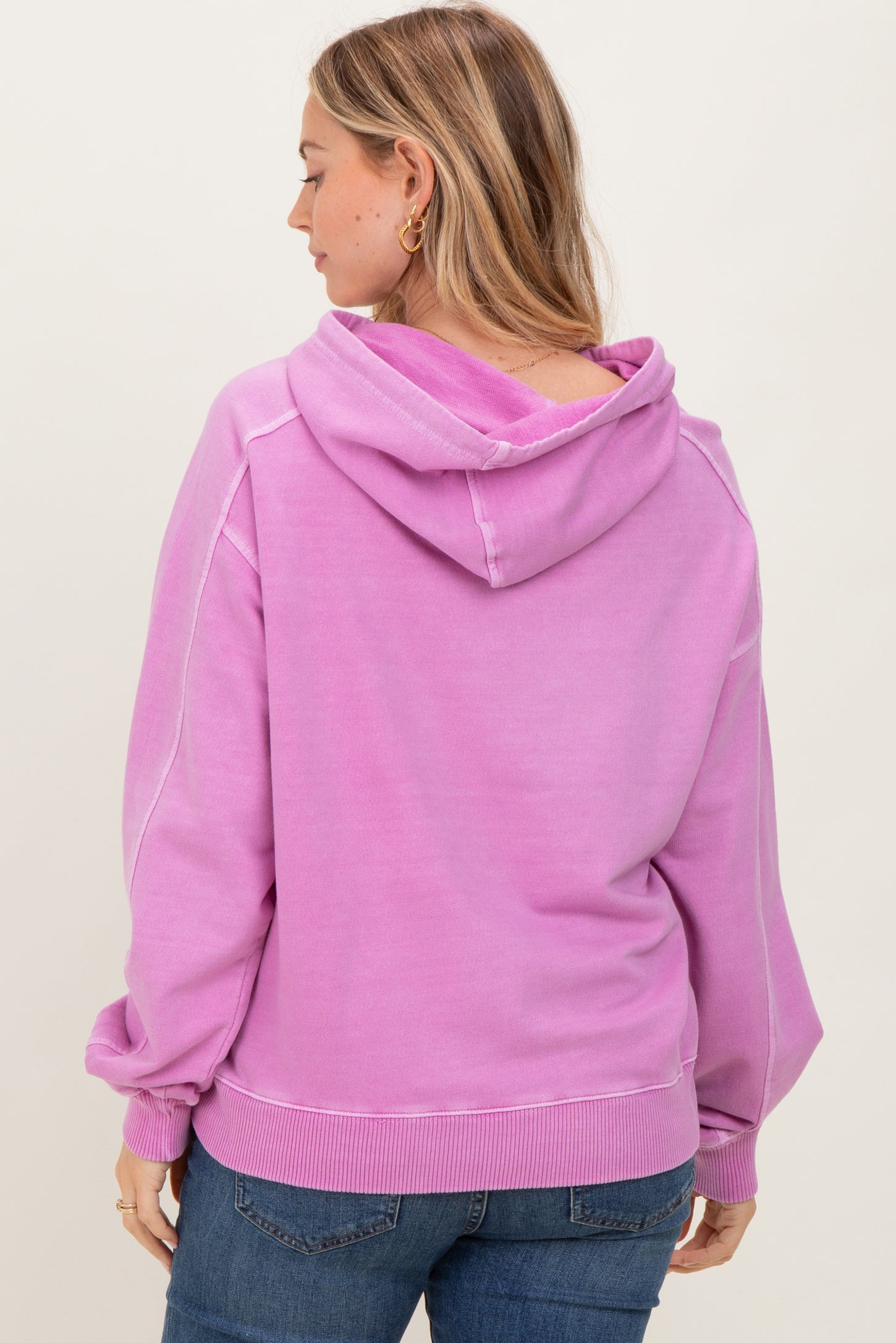 woman wearing a pink hooded sweatshirt with a relaxed fit and ribbed hem, viewed from the back
