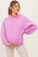 woman wearing a light pink maternity hoodie and holding her baby bump