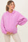woman wearing a light pink maternity hoodie and holding her baby bump
