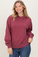 woman wearing a burgundy oversized hoodie with a drawstring and long sleeves, smiling while posing