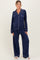 woman wearing a navy blue long sleeve maternity pajama set with white piping details and loose-fitting trousers
