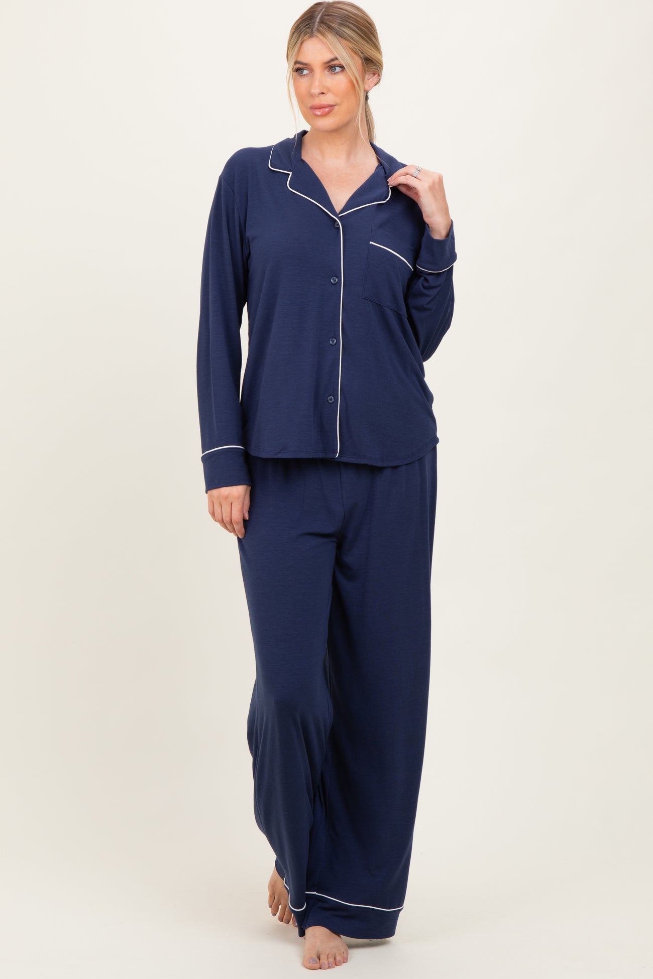 woman wearing a navy blue long sleeve pajama set with white piping and wide-leg pants