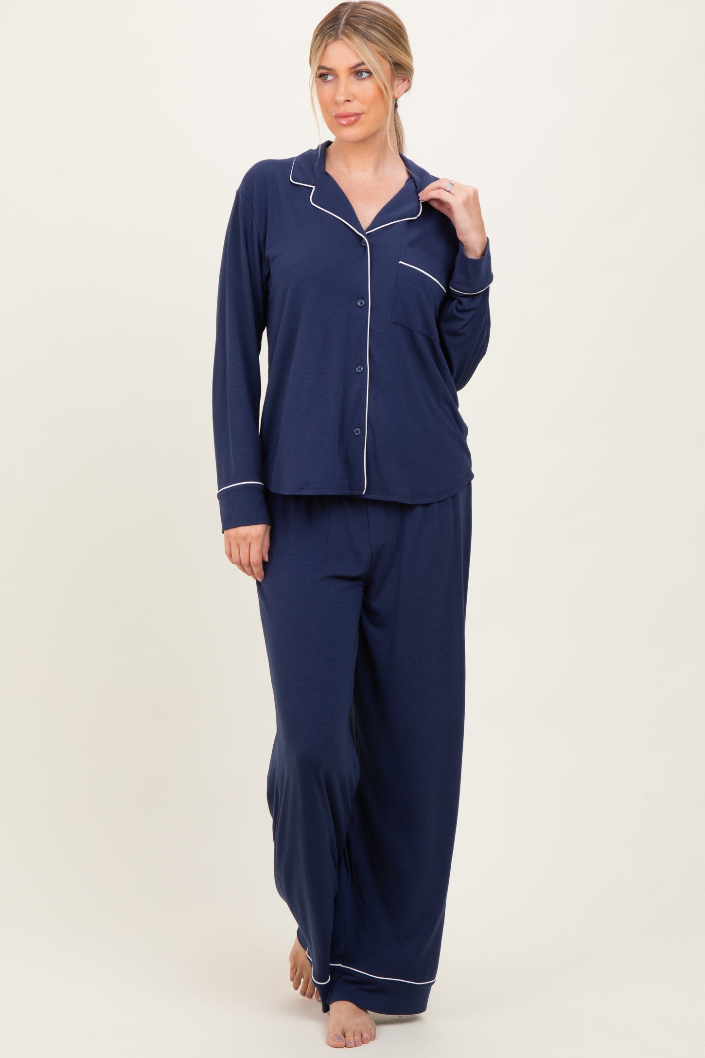 woman wearing a navy blue long sleeve pajama set with white piping and wide-leg pants