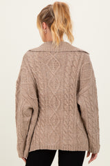 woman wearing a beige oversized cable knit maternity sweater viewed from the back
