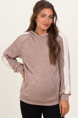 woman wearing a light brown maternity hoodie with ribbed texture and white stripes on the sleeves, hands in pockets