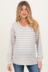 woman wearing a striped light gray and white maternity sweater with a v-neck and long sleeves, styled casually