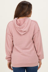 woman wearing a dusty pink ribbed hoodie, showing the back view, designed for maternity wear