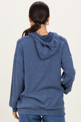 woman wearing a slouchy blue hooded sweater with ribbed texture and a relaxed fit, shown from the back
