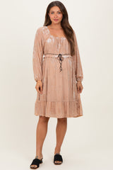 woman wearing a blush pink floral maternity dress with long sleeves and a drawstring waist, showing her baby bump