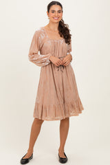 woman wearing a blush pink long sleeve dress with floral print and tiered ruffle hem, styled with flat black shoes