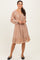 woman wearing a blush pink long sleeve dress with floral print and tiered ruffle hem, styled with flat black shoes