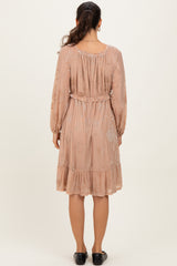 woman wearing a blush pink long sleeve dress with a cinched waist and ruffled hem, seen from the back