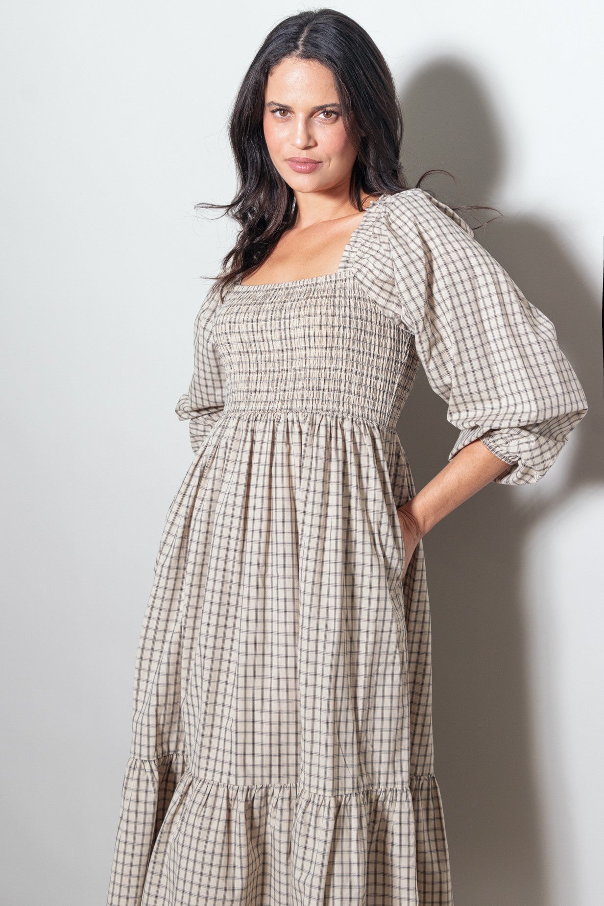 woman wearing a beige checkered puff sleeve maxi dress with smocked bodice and pockets