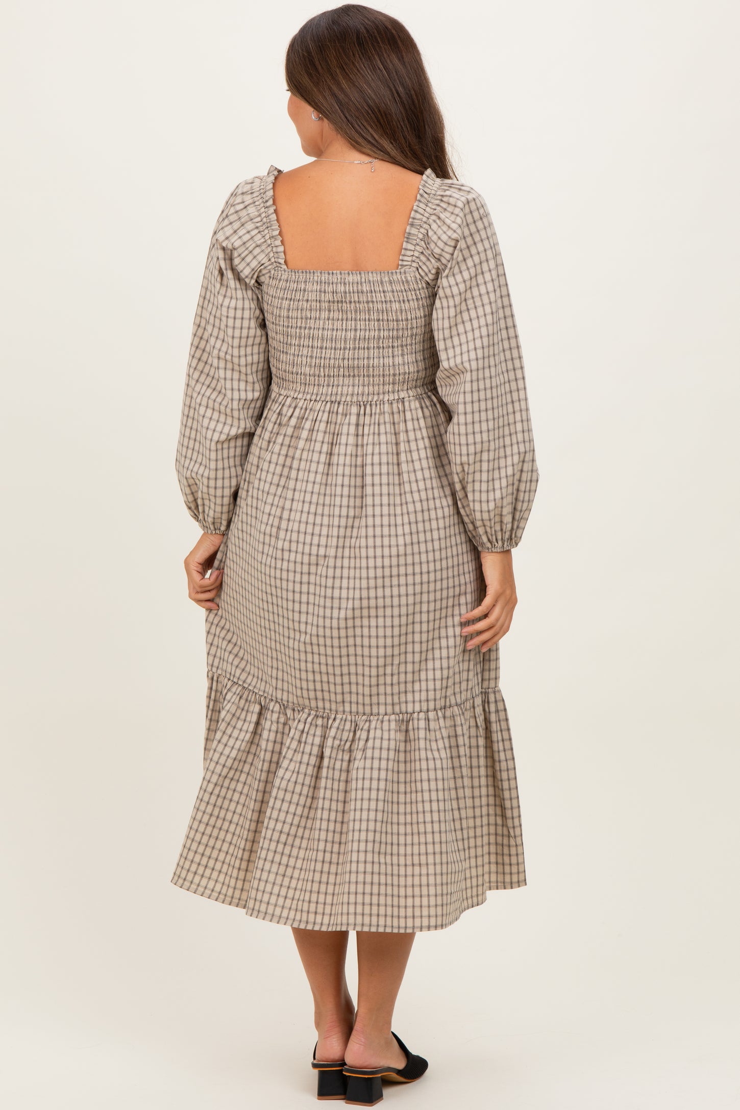 woman wearing a brown and cream checkered maternity dress with long puff sleeves and a ruffled hem