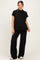 woman wearing a black ribbed maternity top and matching wide-leg pants, showing a visible baby bump