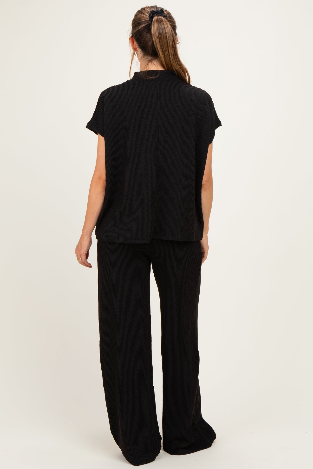 woman wearing black maternity top and matching wide-leg pants, viewed from the back