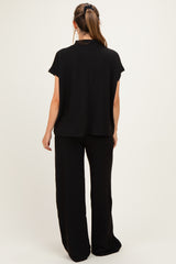 woman wearing black maternity top and matching wide-leg pants, viewed from the back