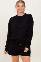 woman wearing a black oversized sweatshirt with long sleeves and coordinating black shorts