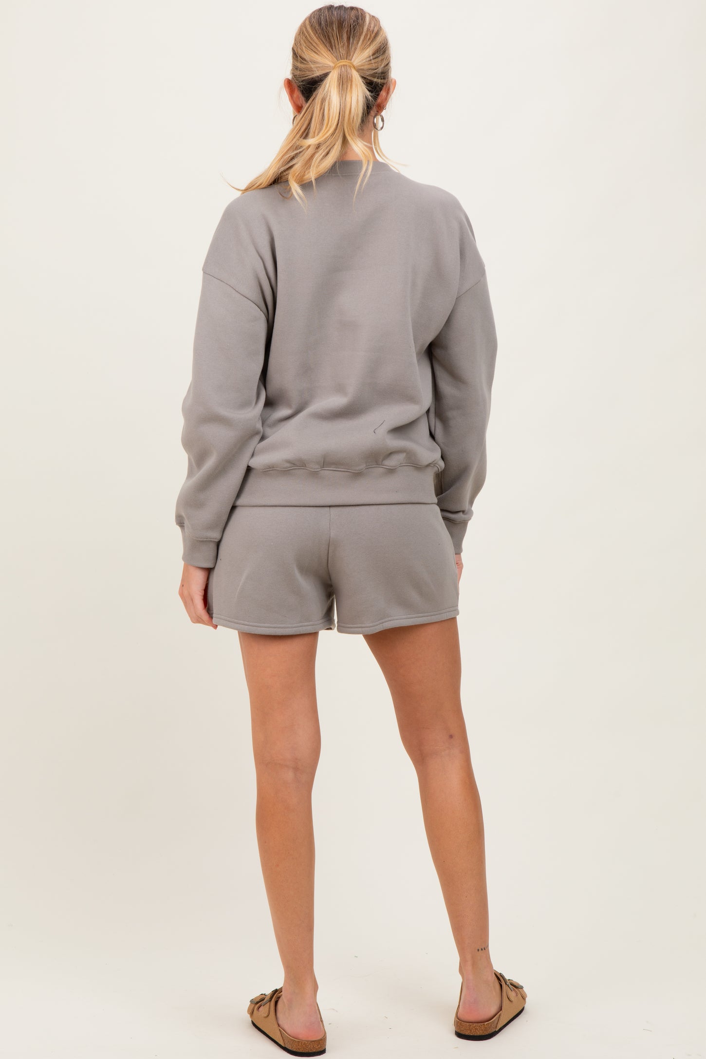 woman wearing a gray maternity sweatshirt and shorts, showing her back and a relaxed fit