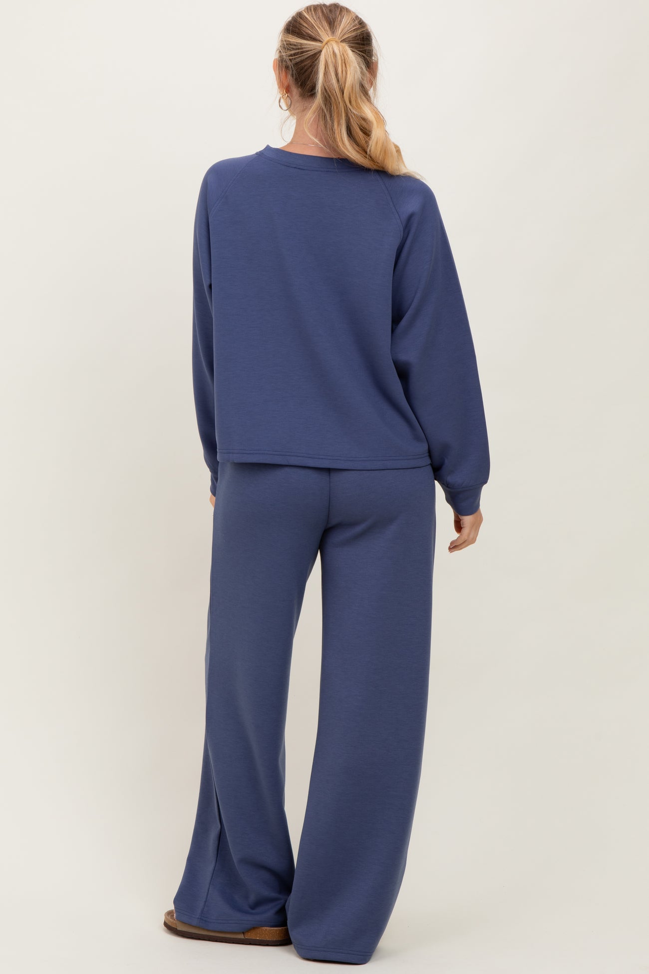 woman wearing a dark blue relaxed sweatshirt and matching wide-leg pants, shown from the back