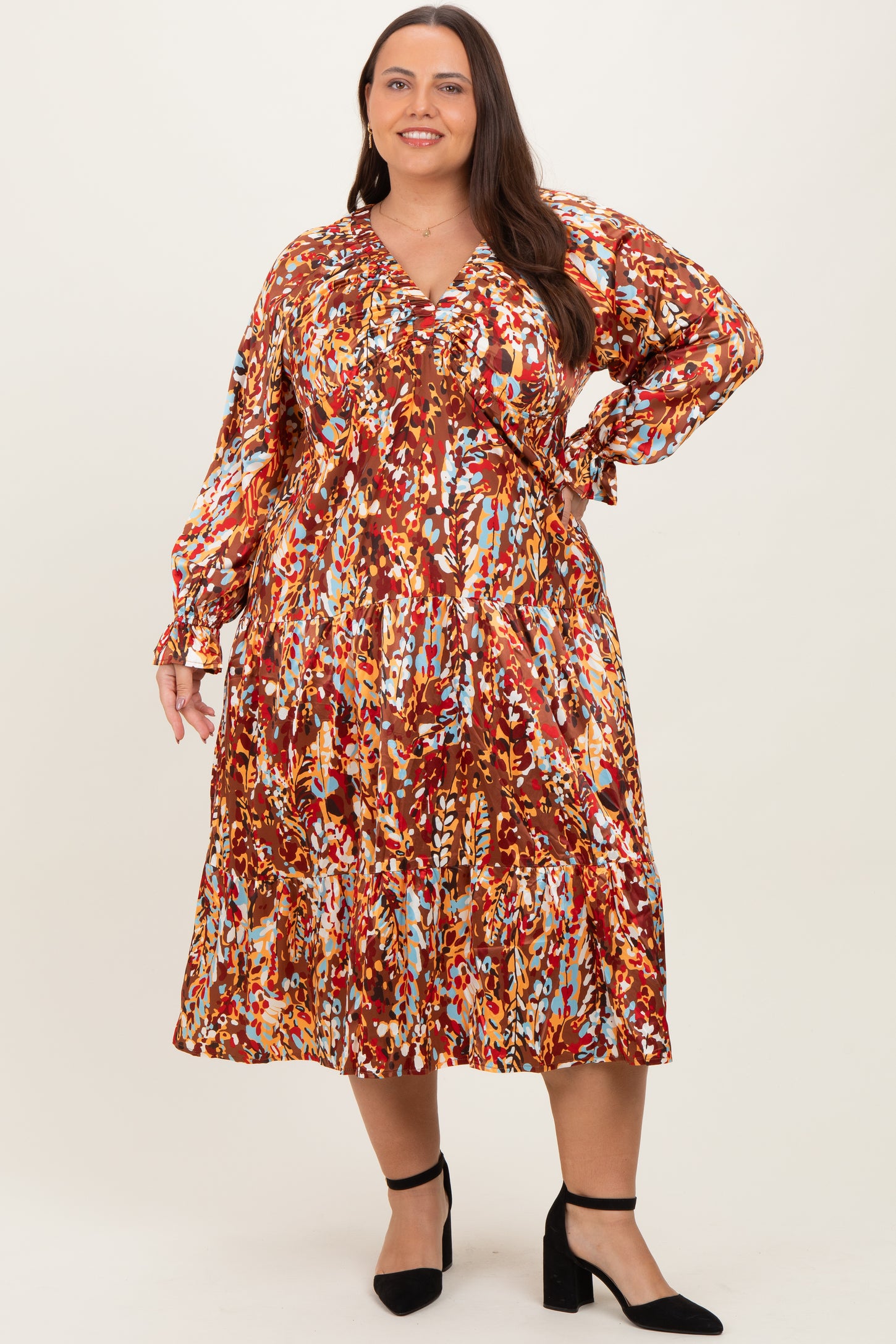 plus-size woman wearing a colorful printed long sleeve dress with a v-neckline and tiered skirt