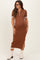 woman wearing a brown short sleeve maternity midi dress with white accents and side slit, styled with white ankle boots