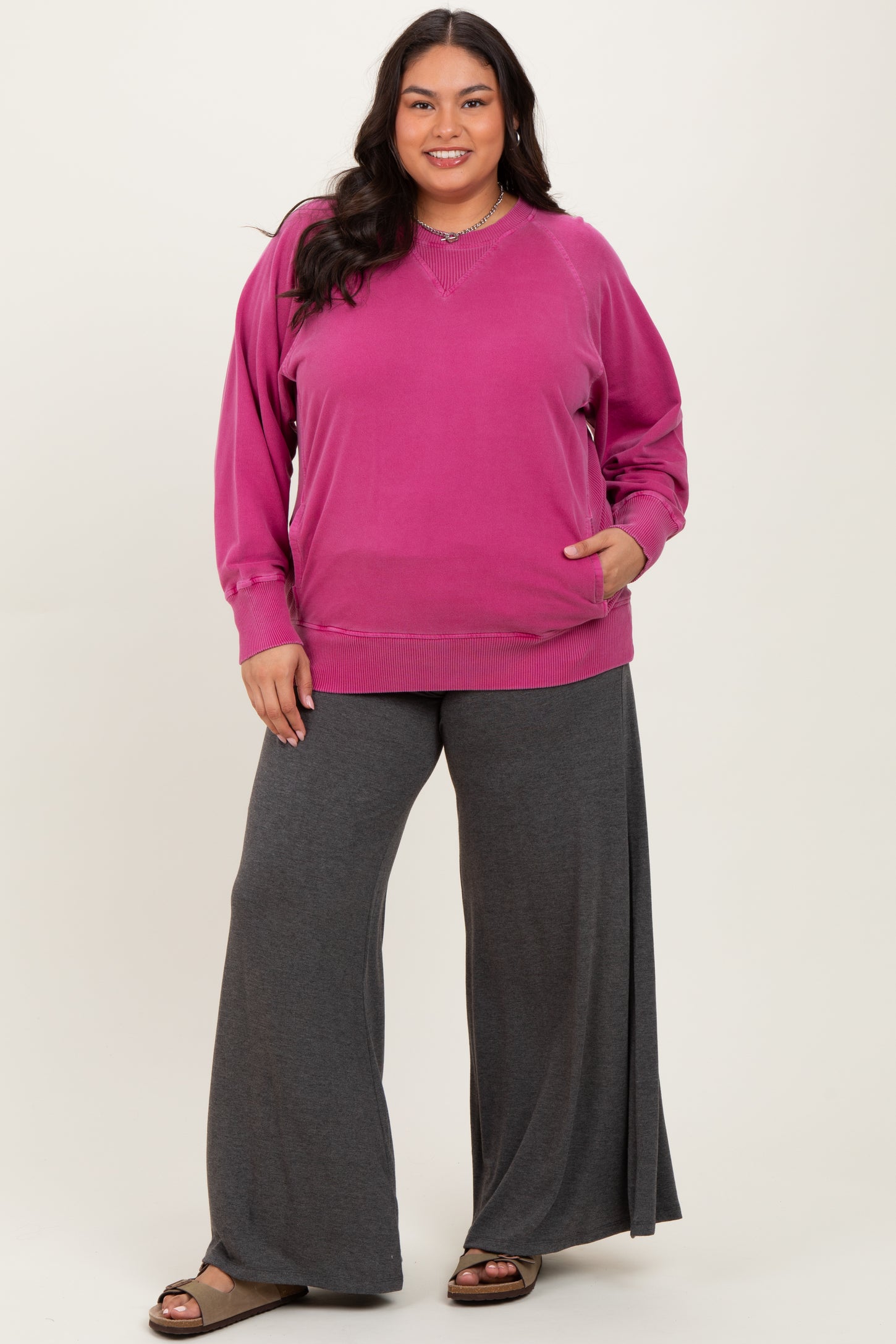 woman wearing a pink oversized sweatshirt with a v-neck and gray wide-leg pants