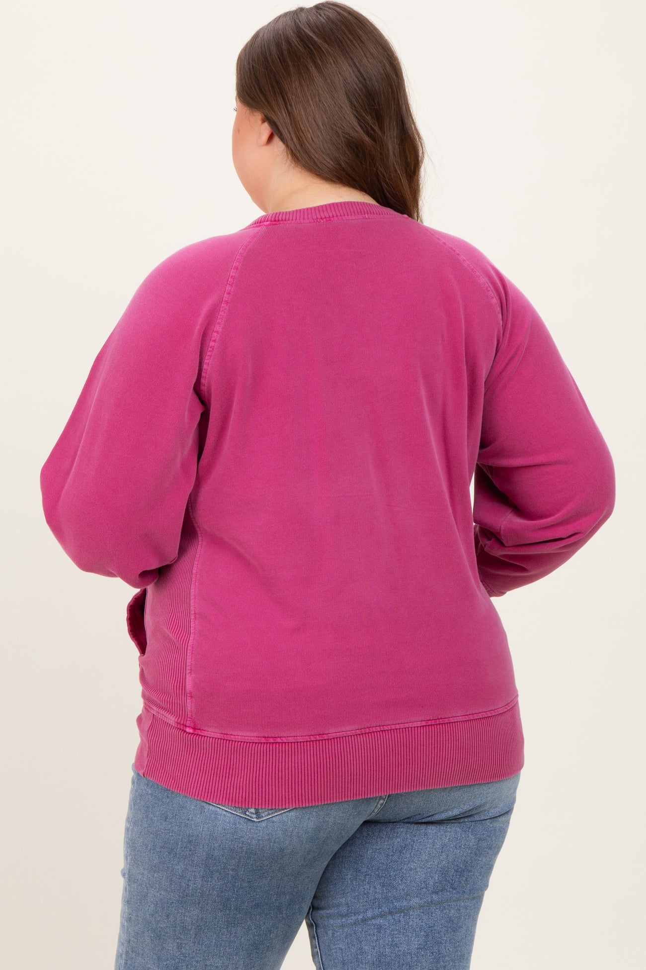 woman wearing a pink maternity plus sweatshirt, viewed from the back, with relaxed fit and ribbed hem