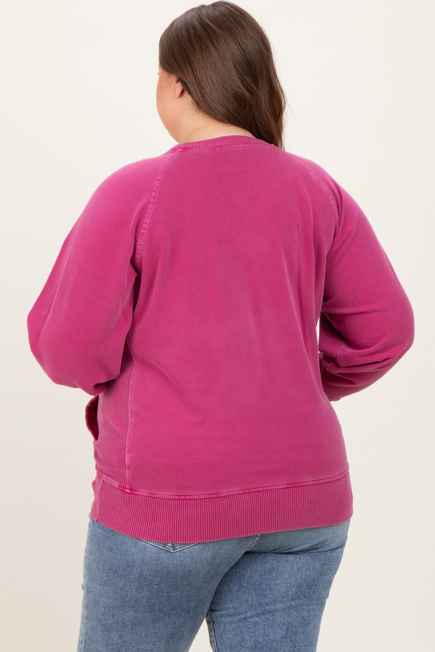 woman wearing a pink maternity plus sweatshirt, viewed from the back, with relaxed fit and ribbed hem