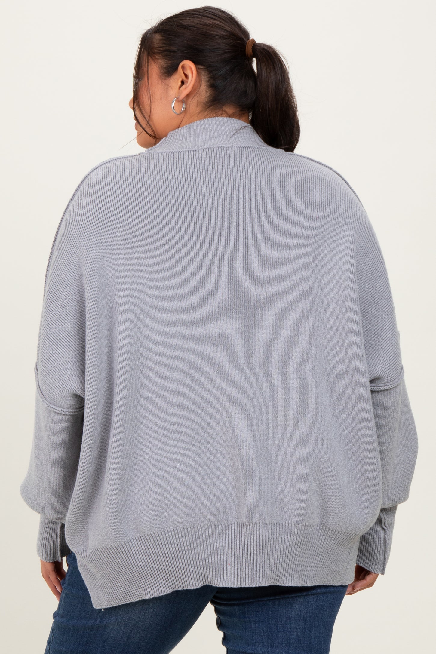 woman wearing a gray oversized sweater with a ribbed texture, viewed from the back