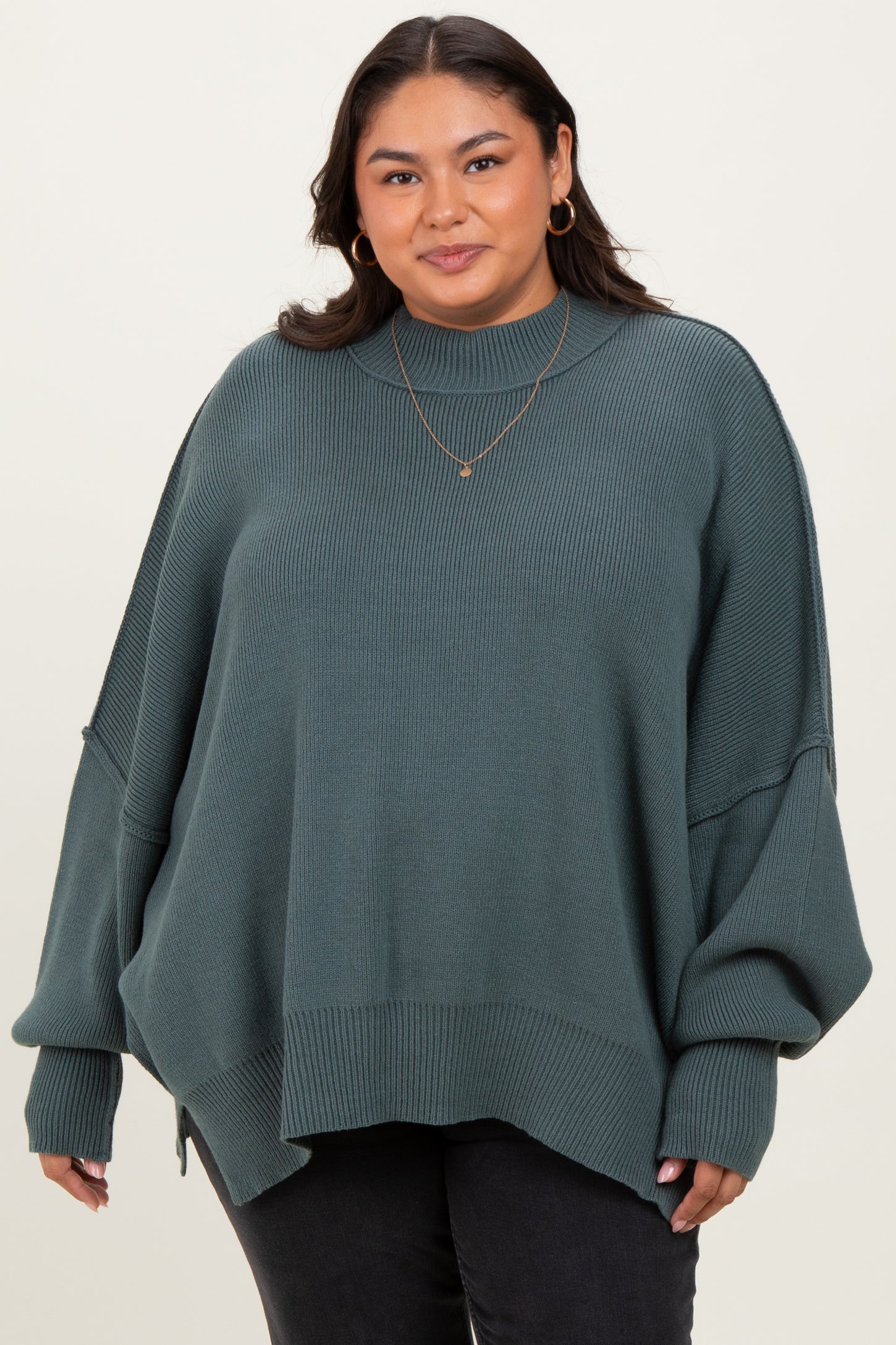 woman wearing a green oversized ribbed sweater with balloon sleeves and a high neckline, paired with black jeans