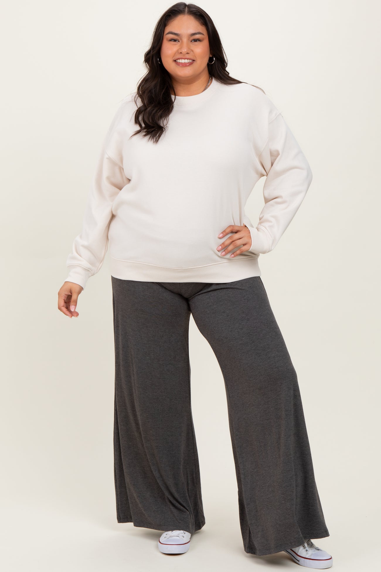 woman wearing a cream oversized sweatshirt and gray wide-leg pants