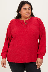 woman wearing a red plus size long sleeve henley top with button details and relaxed fit