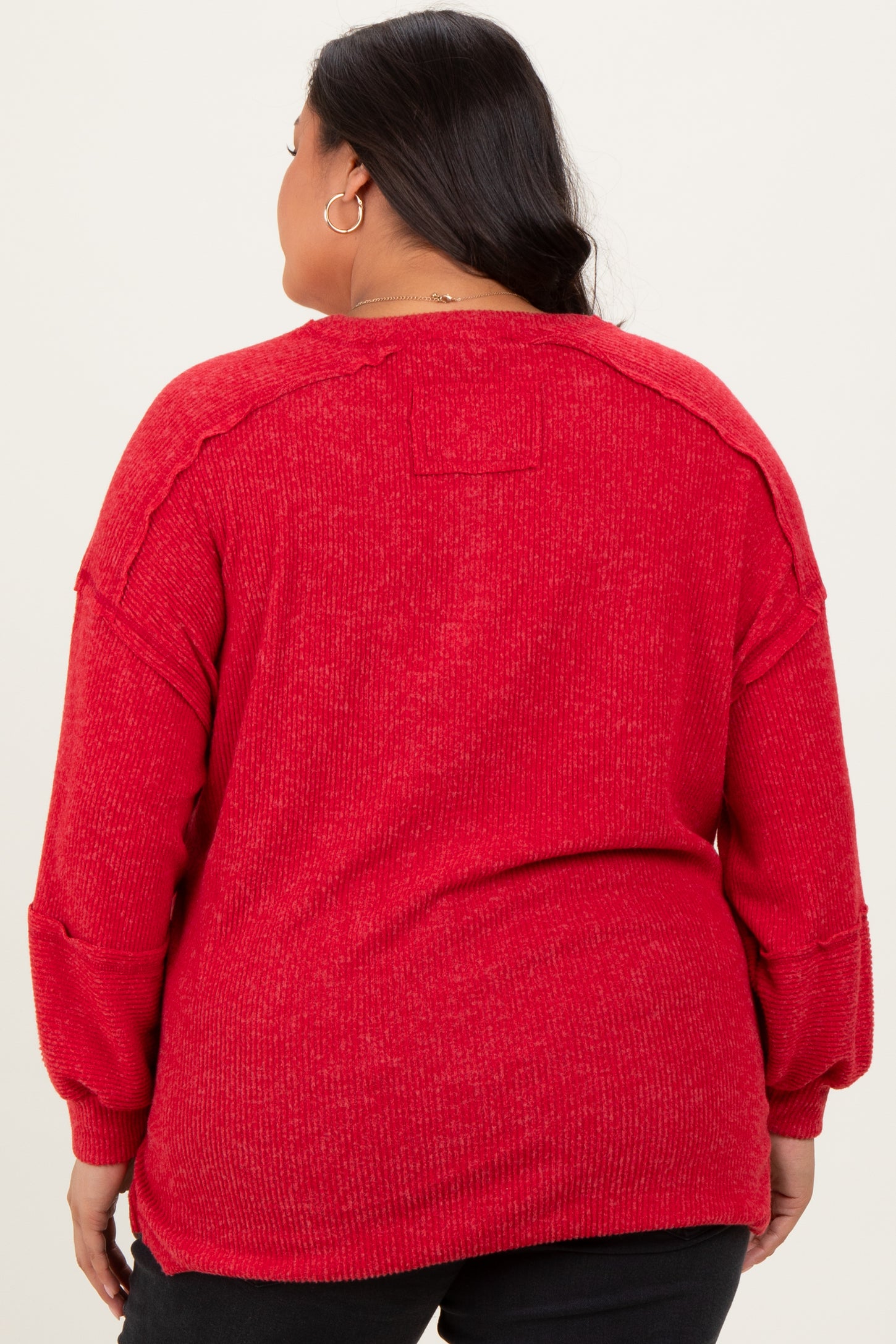 plus size woman wearing a red oversized knit sweater with drop shoulders and long sleeves