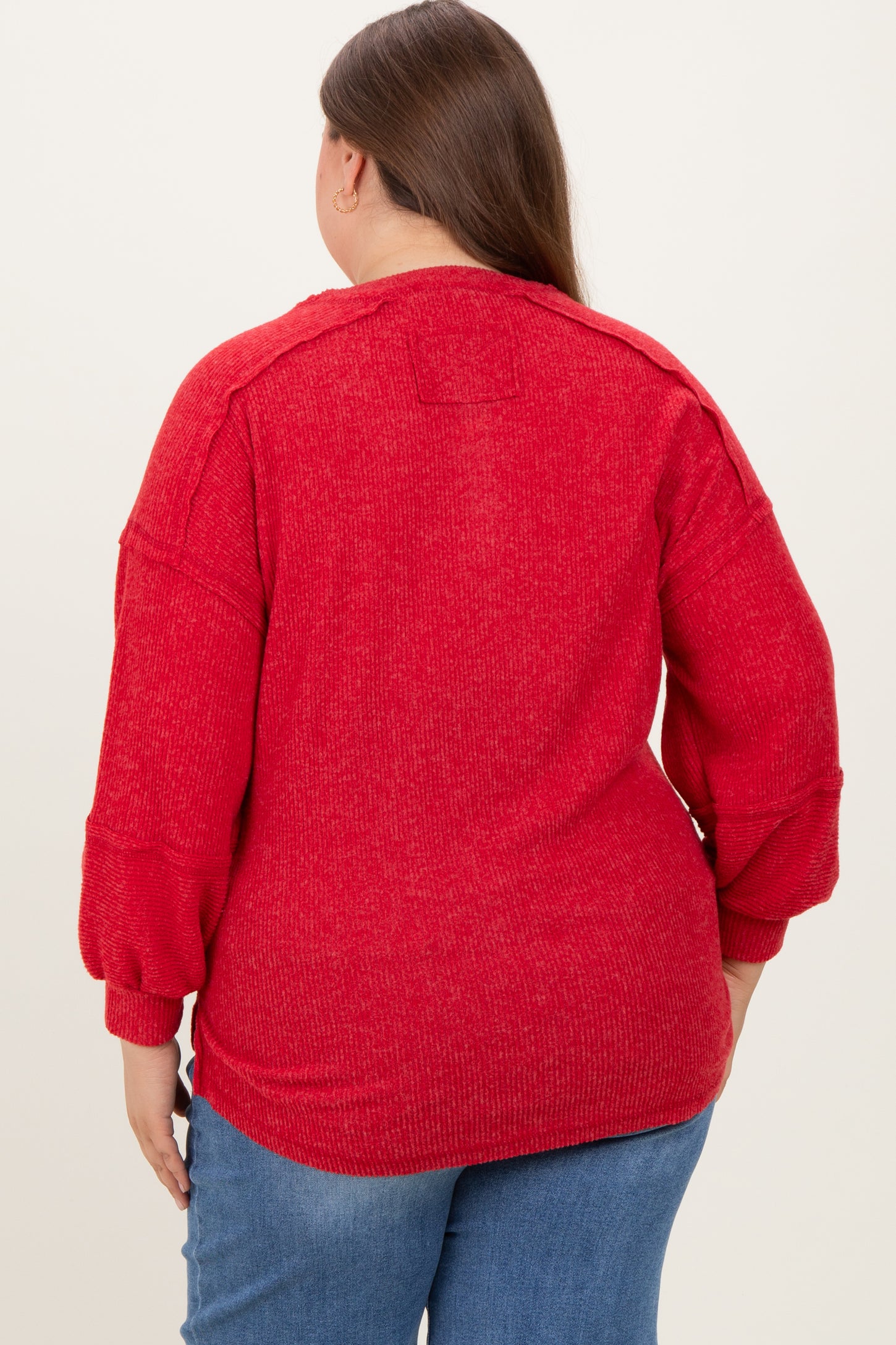 woman wearing a red plus size maternity sweater with balloon sleeves, showing the back view and relaxed fit