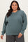 woman wearing a teal oversized sweatshirt with long sleeves and a relaxed fit paired with gray sweatpants