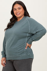 woman wearing a teal plus-size sweatshirt with side panel details and a relaxed fit, smiling at the camera