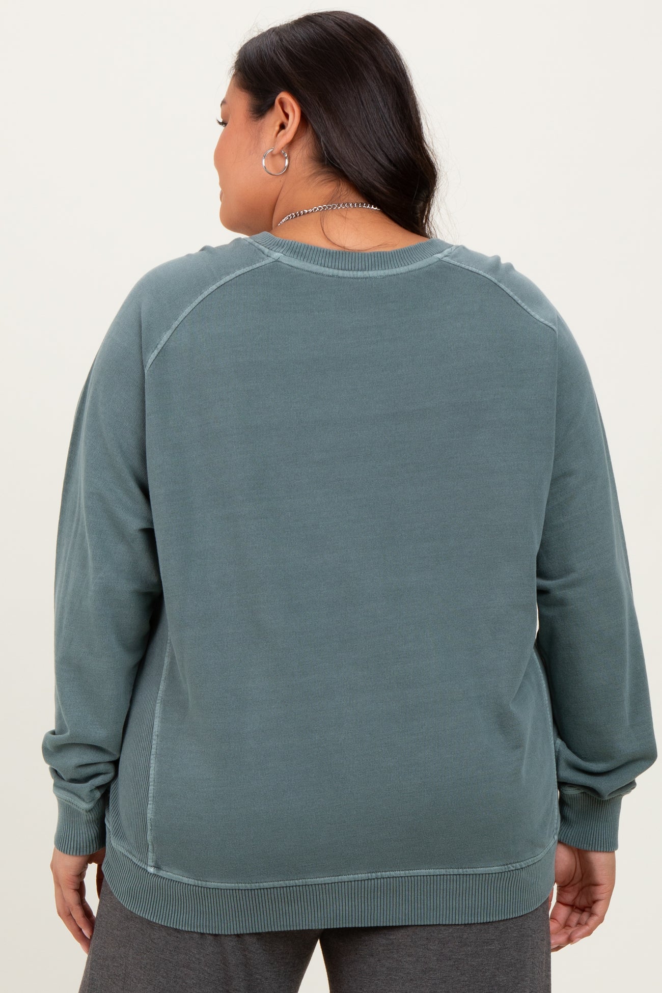 woman wearing a back view of a teal oversized sweatshirt with long sleeves and ribbed hem in plus size