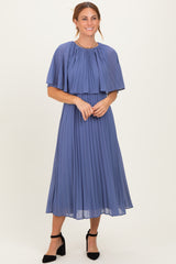 woman wearing a pleated midi dress in soft blue with a cape-style overlay and elegant black heels