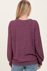 woman wearing a maroon oversized sweater with a relaxed fit, viewed from the back, paired with light blue jeans
