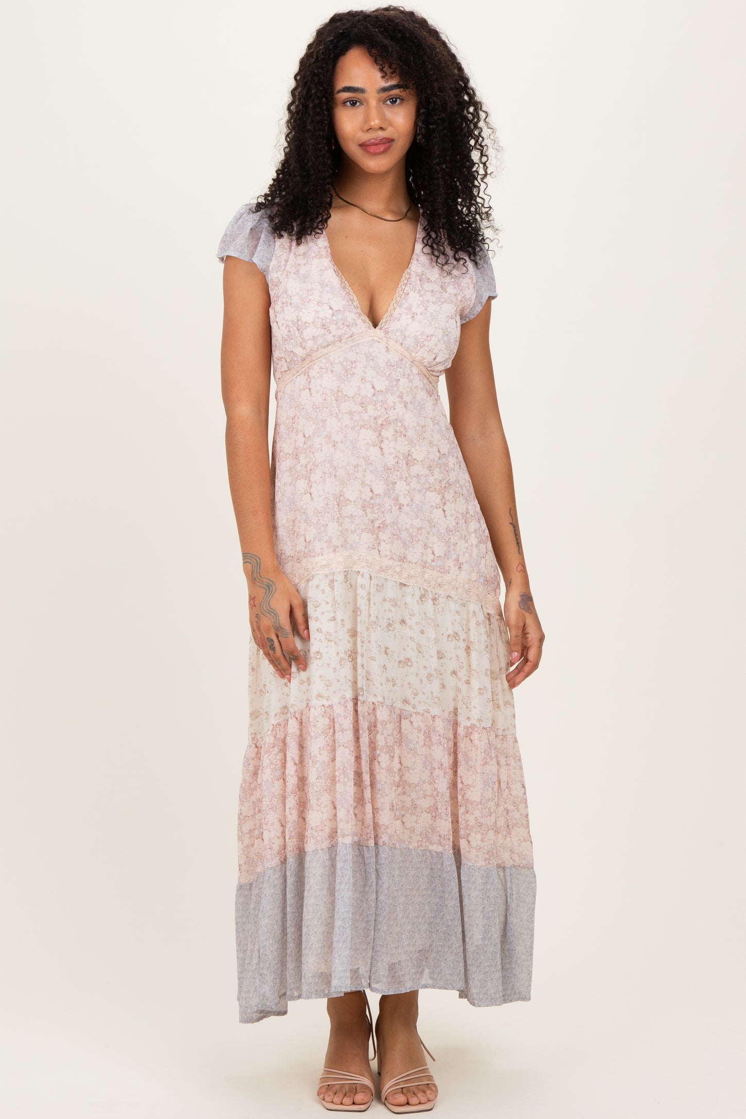 woman wearing a floral maxi dress with a v-neckline and flutter sleeves in pastel colors