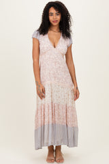 woman wearing a floral maxi dress with a v-neckline and flutter sleeves in pastel colors