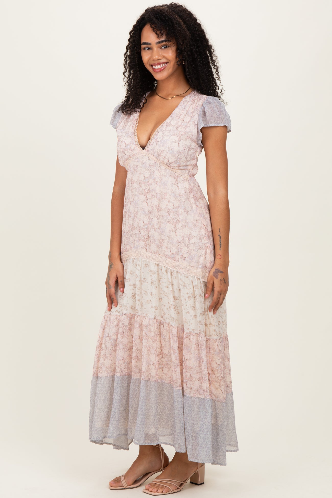 woman wearing a floral print maxi dress with a deep v-neck and short sleeves, standing and smiling