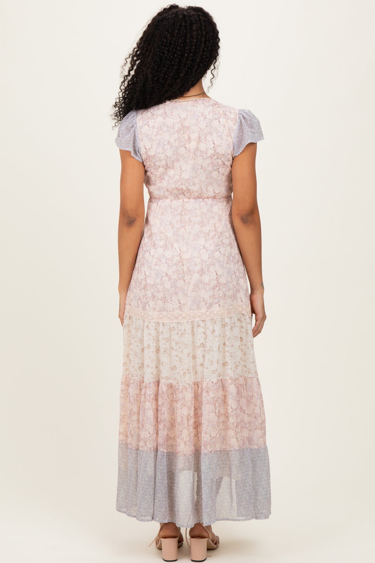 woman wearing a floral maxi dress with short sleeves and tiered hem, showing the back view