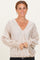 woman wearing a beige polka dot blouse with a v-neck and smocked long sleeves