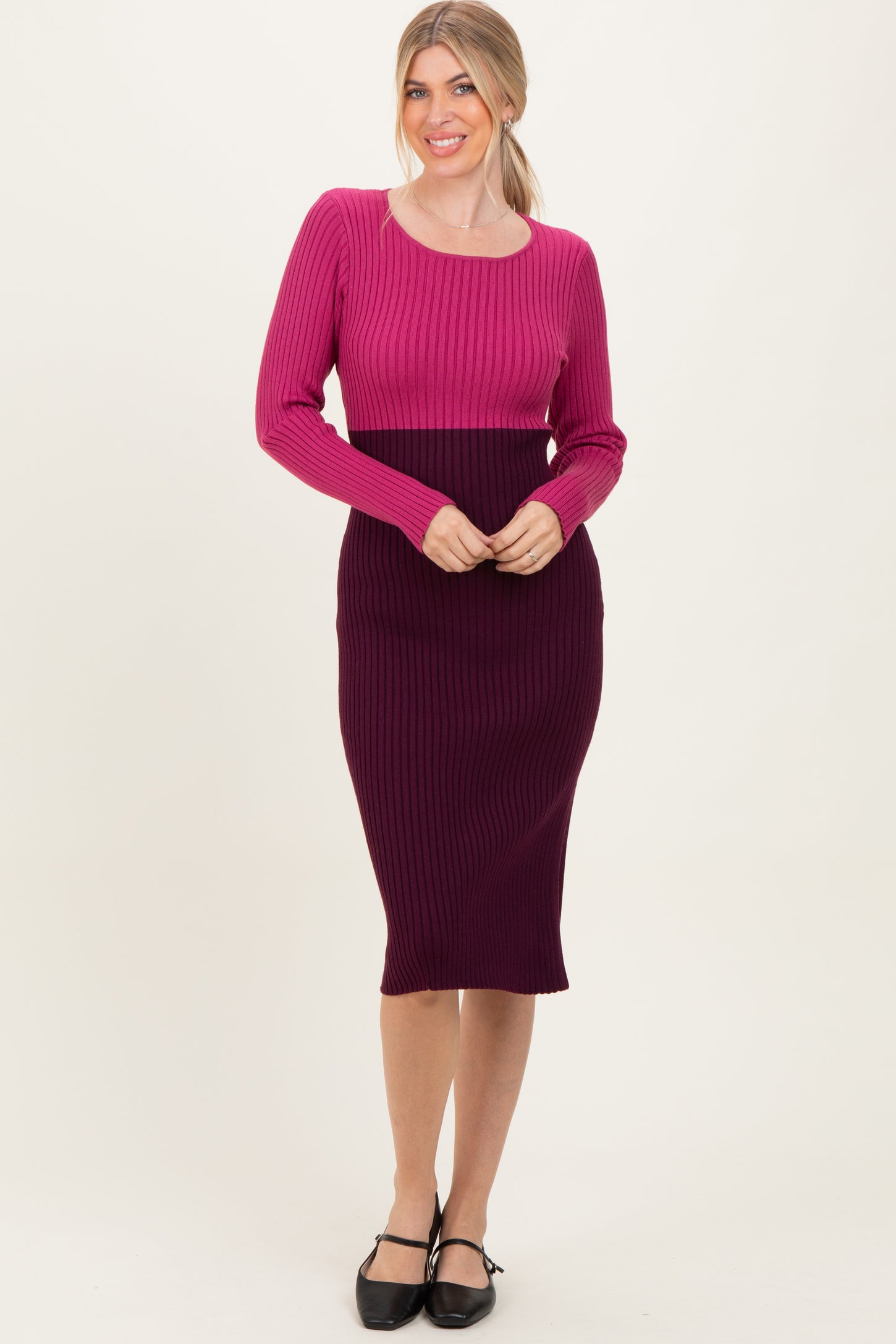 woman wearing a pink and purple ribbed knit midi dress with long sleeves and a fitted silhouette