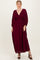 woman wearing a burgundy maxi dress with a deep v-neck and smocked bodice, styled with a flowy skirt and balloon sleeves