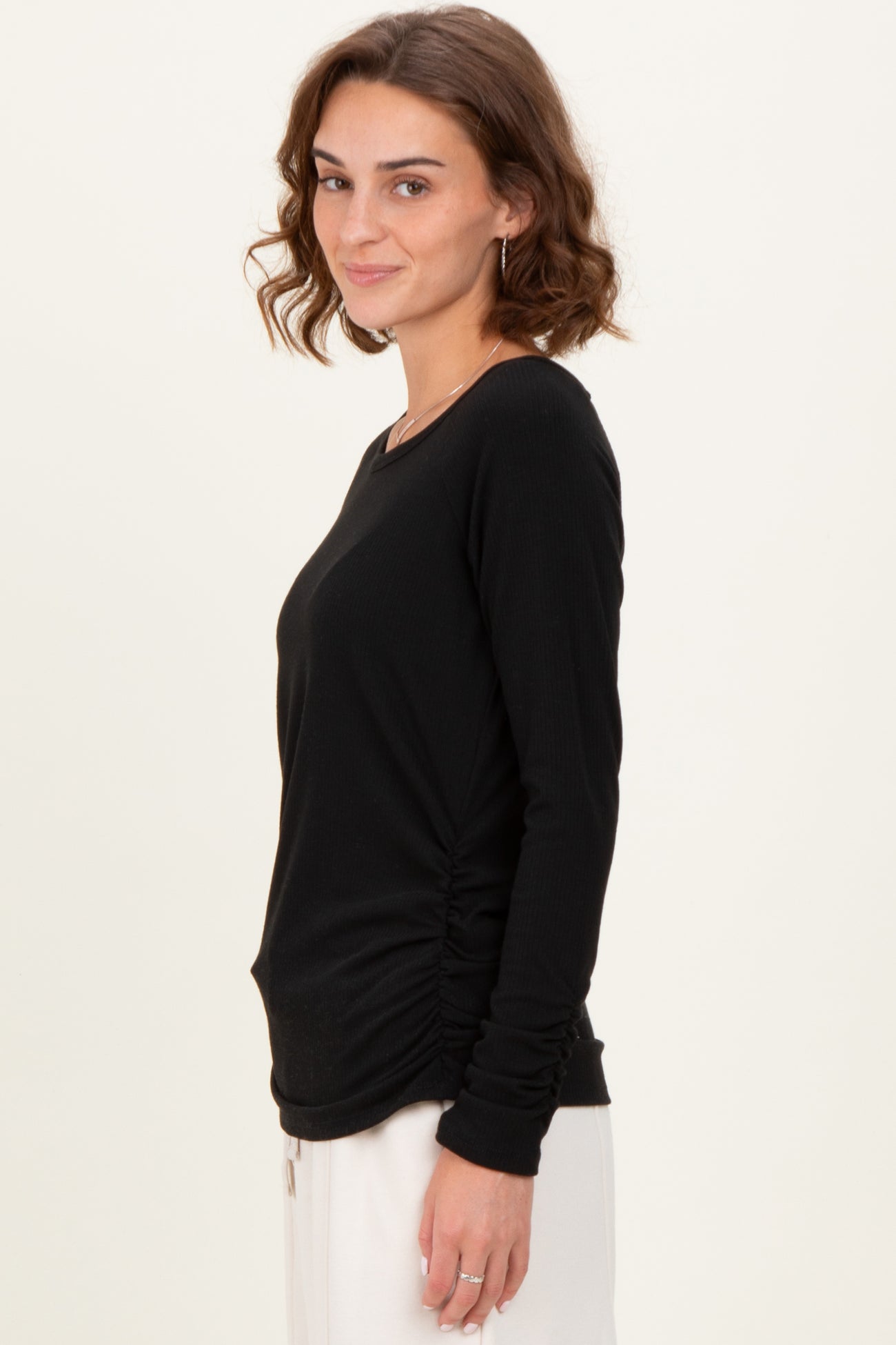 woman wearing a black long sleeve ribbed top with side ruching and a round neckline
