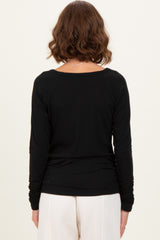 woman wearing a black long sleeve ribbed top, viewed from the back, paired with cream-colored pants
